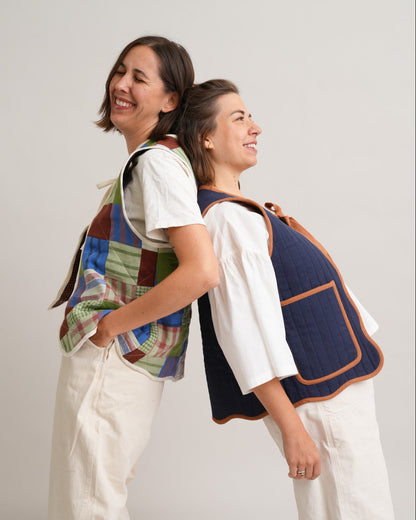 Two women wearing colorful vests against a plain background