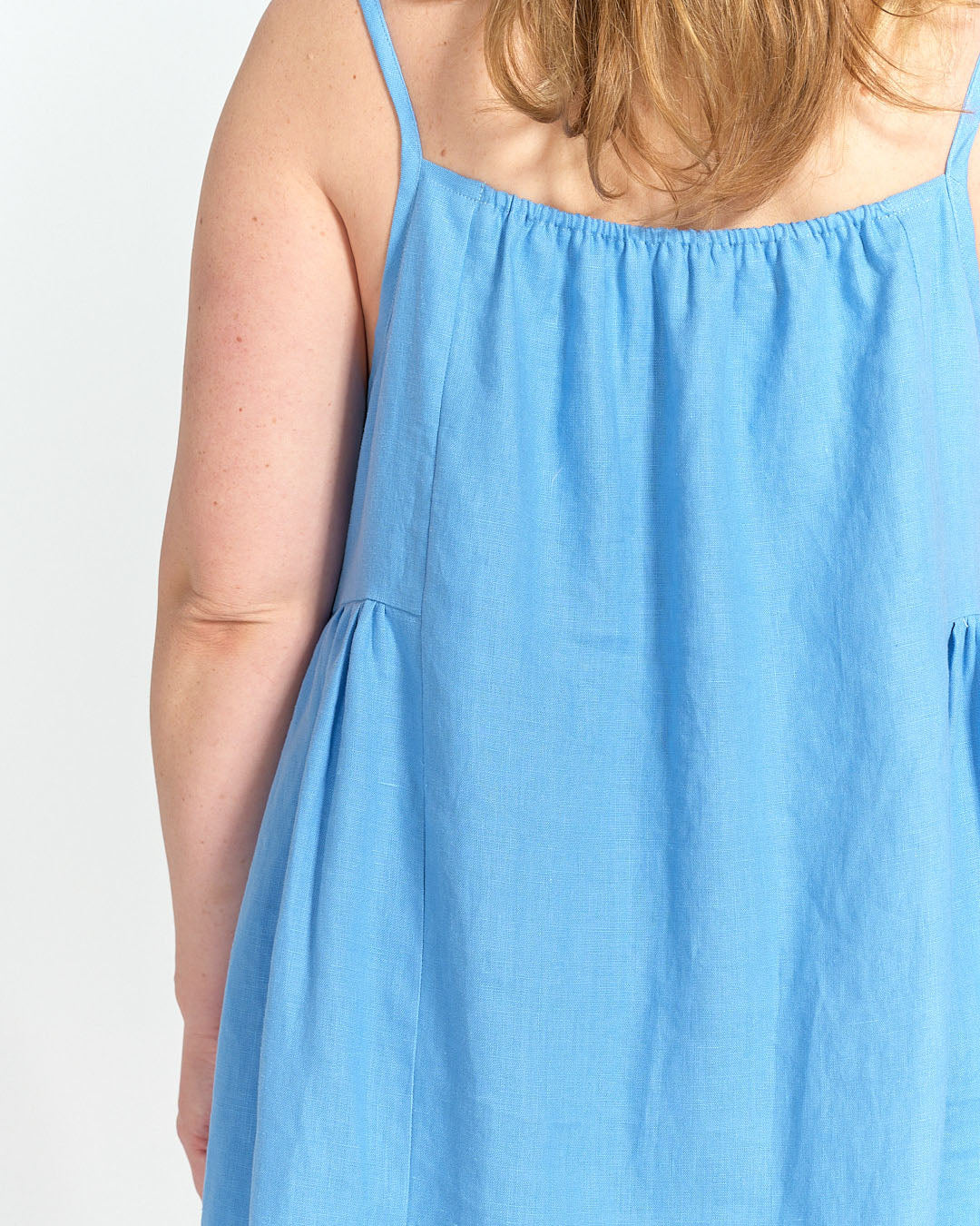 Back view of Schoolhouse Sundress with elastic channel neckline and relaxed fit in blue linen
